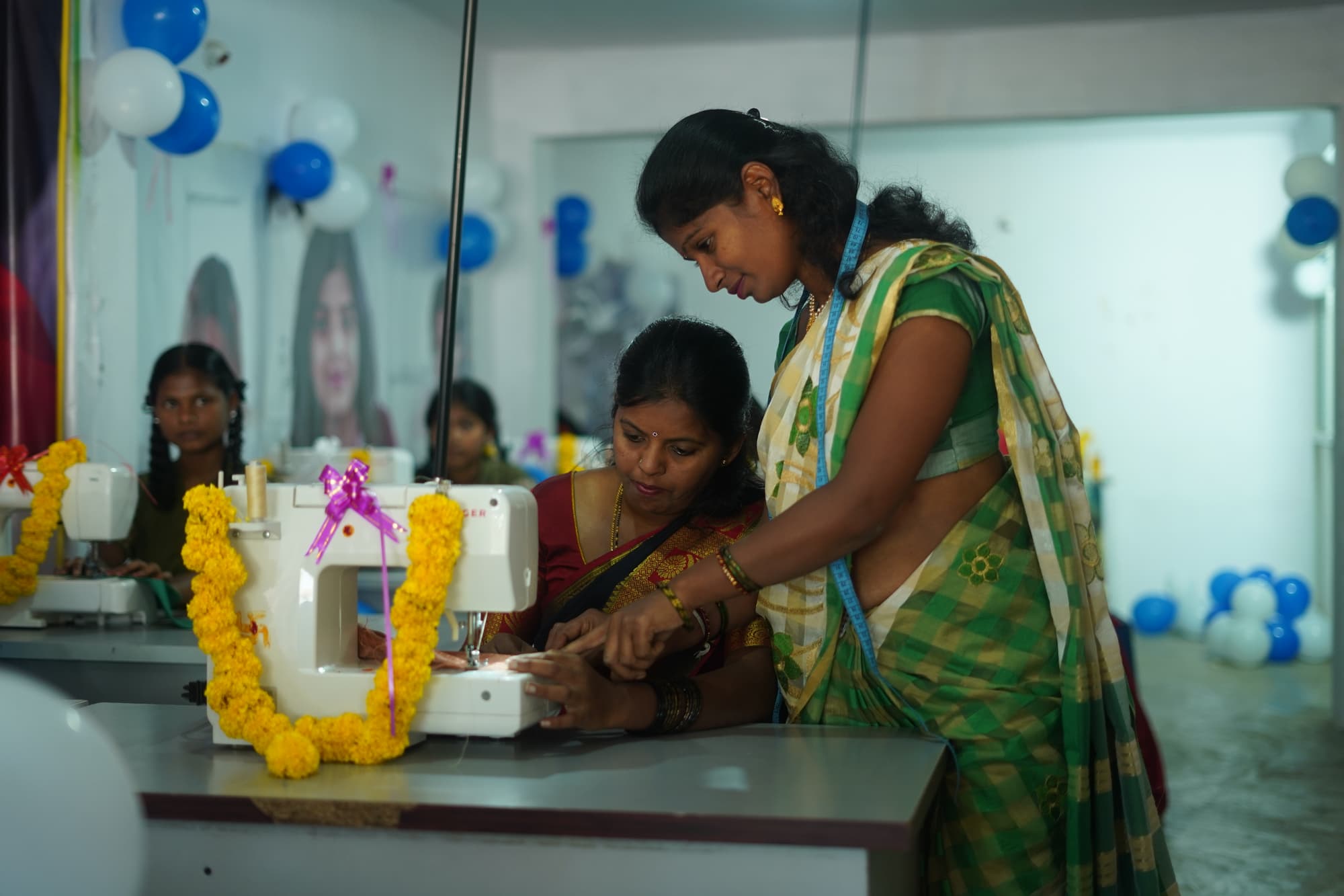 A trainer guiding a woman at a sewing machine in an Aahwahan skill-development centre